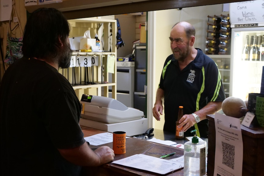 A man serves another man standing at a bar.