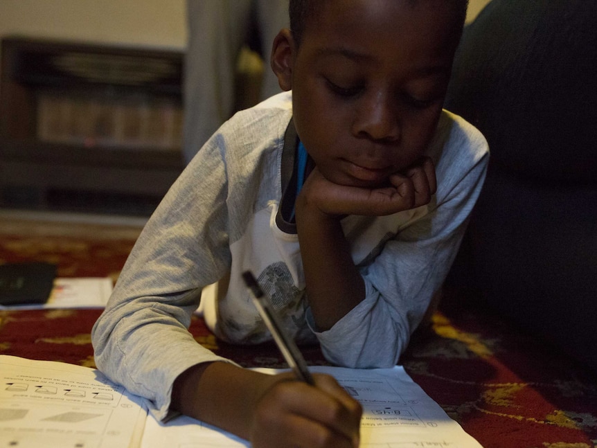 Maher does his homework on the lounge-room floor.