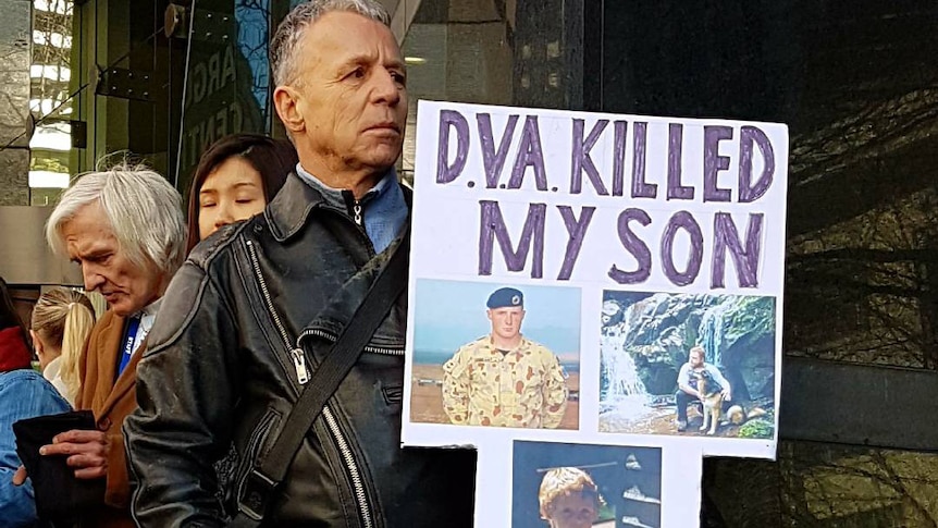Ross Grant holds a sign outside the DVA that reads: "DVA killed my son"