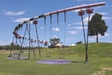 A curved piece of play equipment with swings hanging from it.