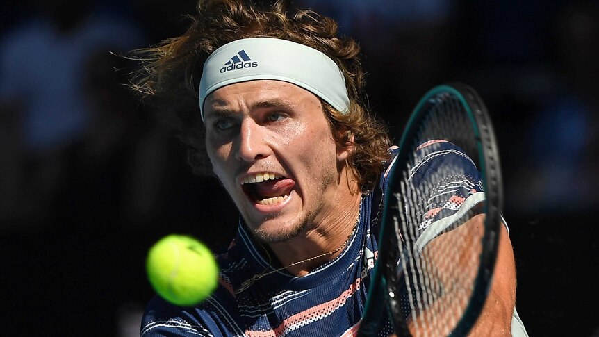 A male tennis player sticks his tongue out as he plays a backhand at the Australian Open.