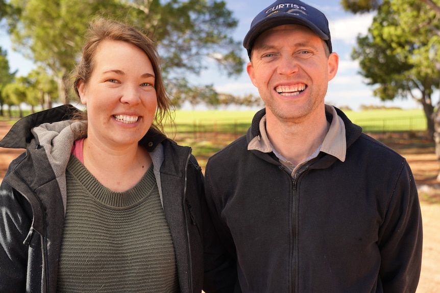 A young couple, outdoors and smiling