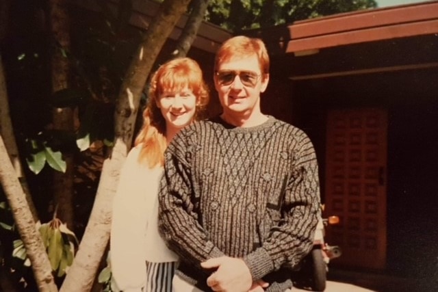 a young woman standing behind a young man