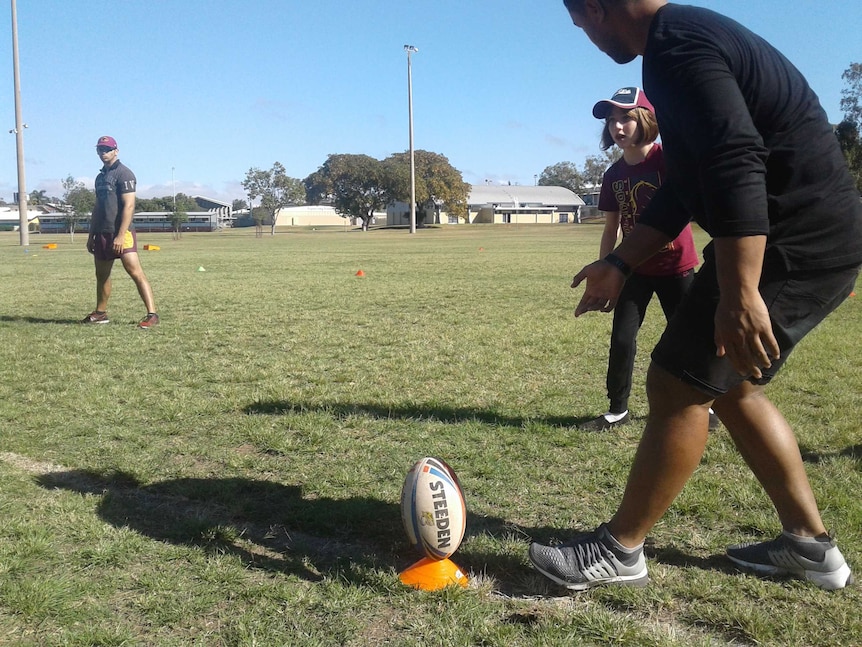 A Capras player helps a girl kick a football