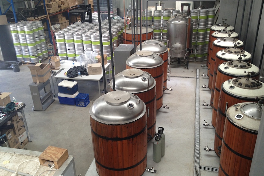 Numerous kegs and brewing vats at a craft brewery.