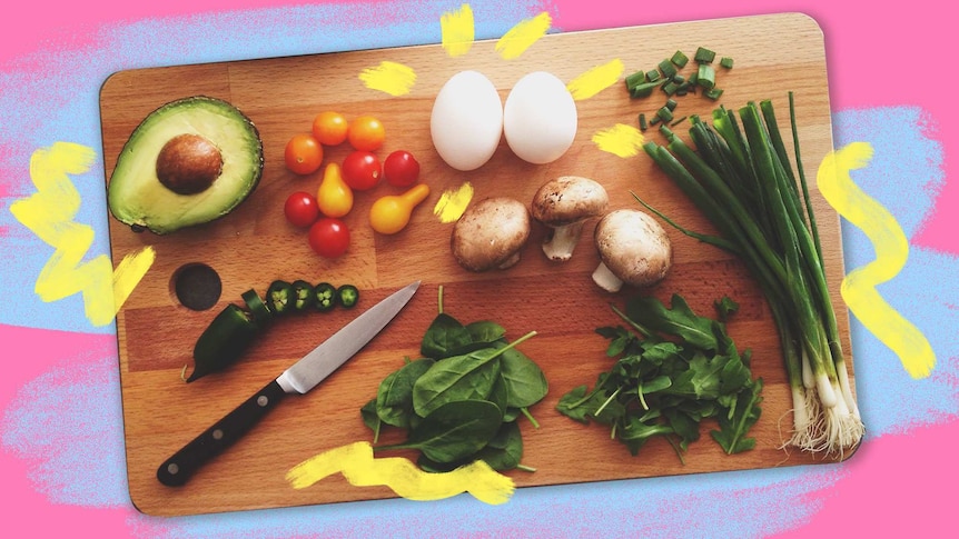 Ingredients on wooden chopping board including avocado, cherry tomatoes, eggs, mushrooms, and shallots