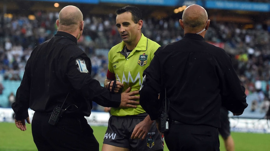 Gerard Sutton escorted from the field at Sydney's Olympic stadium by two security guards.