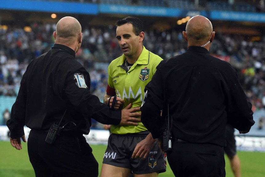 Gerard Sutton escorted from the field at Sydney's Olympic stadium by two security guards.