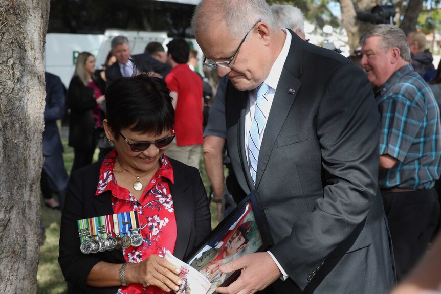 Myrna Walker shows photos of her son in military clothing to the Prime Minister