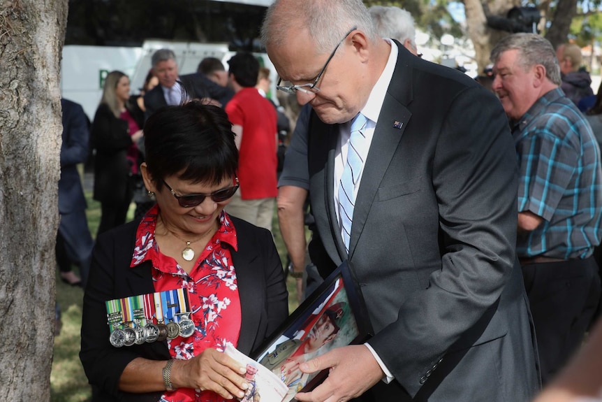 Myrna Walker shows photos of her son in military clothing to the Prime Minister