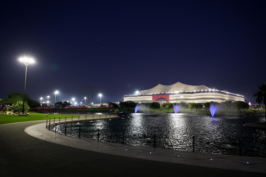 Qatar's Al Bayt Stadium seen from outside under lights.