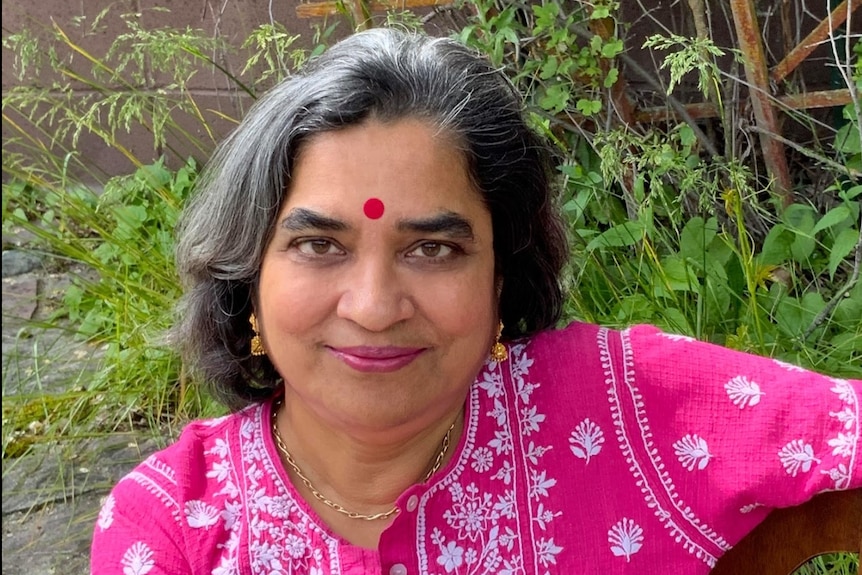 A woman in tradition Indian dress looks at the camera. 