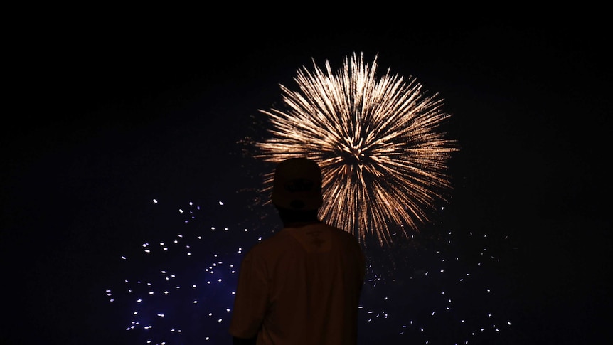 A man watches as fireworks explode over the coast of Vina del Mar as part of New Year celebrations in Chile.