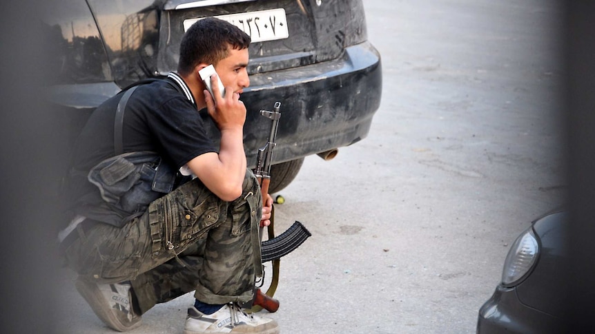 A Syrian rebel talks on a mobile phone during clashes.