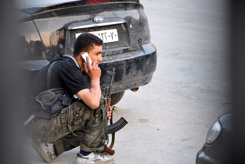 A Syrian rebel talks on a mobile phone during clashes.