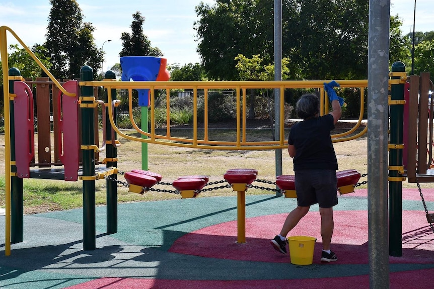 A woman cleans playground equipment at Mango Hill State School.