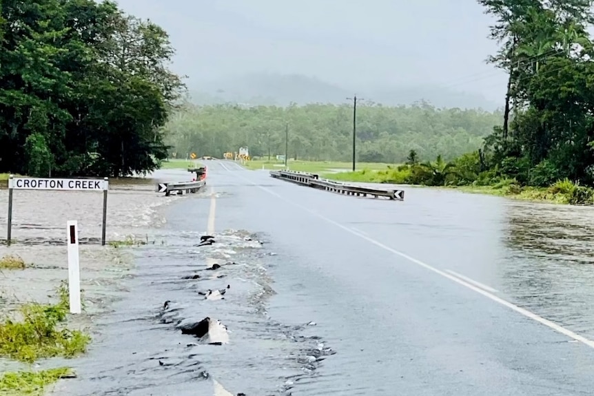 a sign reading crofton creek, a flooded creek and highway