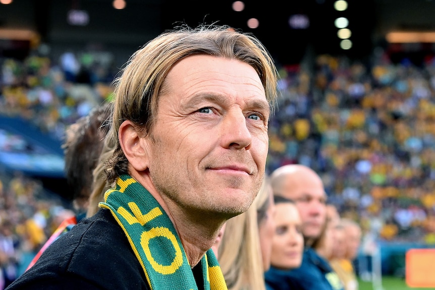Tony, wearing a Matildas scarf, looks up adoringly at fans in the stadium.