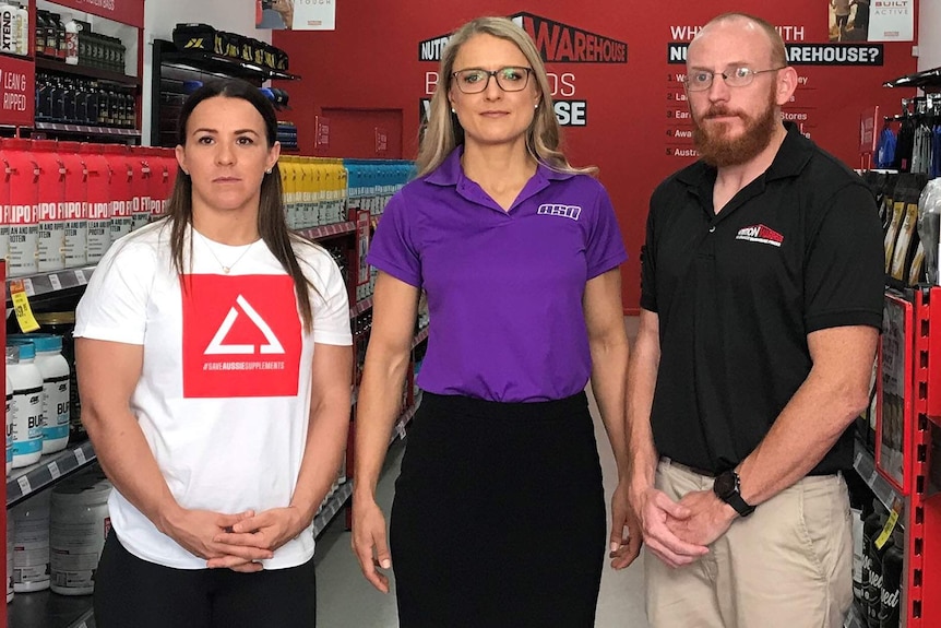 Three people standing inside a warehouse of sports supplements supplies