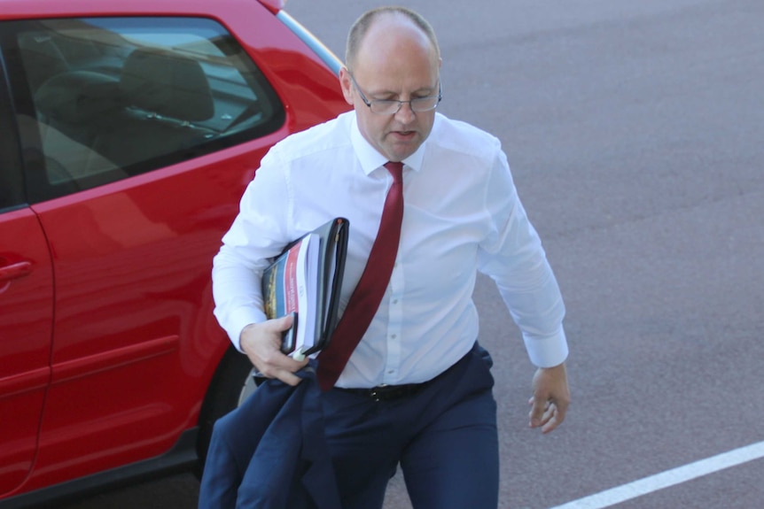 Darling Range MP Barry Urban walks up the stairs outside State Parliament in front of a red car.