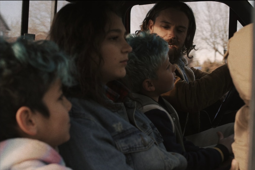 一个男人和三个孩子坐在一辆皮卡车里