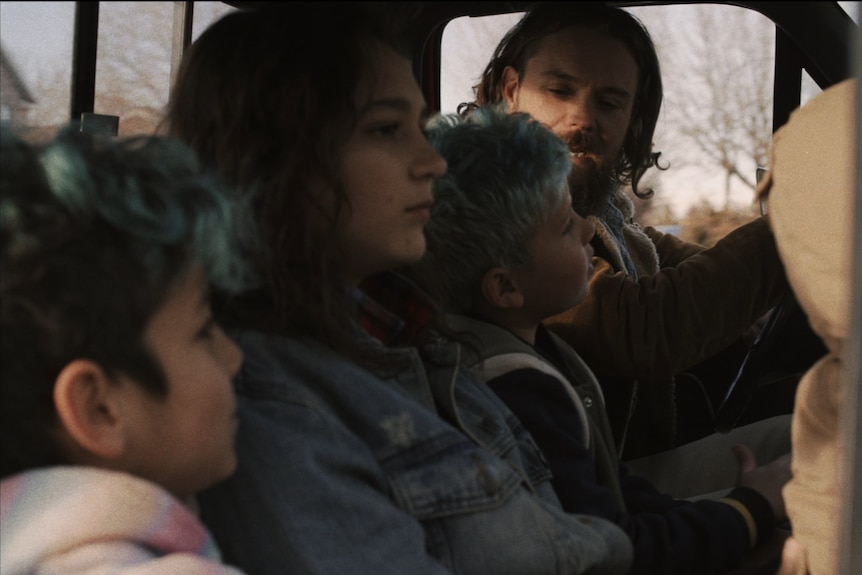 A man and three children sit in a pick-up truck