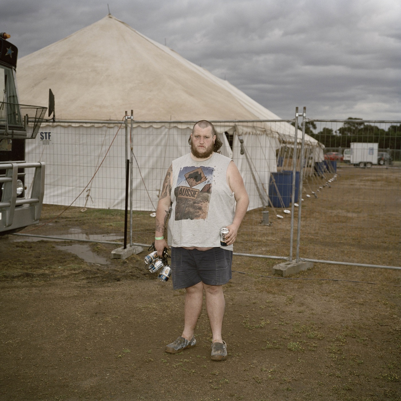 A man with a six pack of alcohol at a dusty ball site.