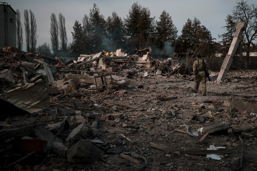 A soldier walks on the debris of a car wash