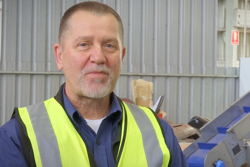 A greying man with short hair and beard looks at the camera.