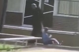 A man is shown dragging a boy through a school playground by his arm in a still from a video.