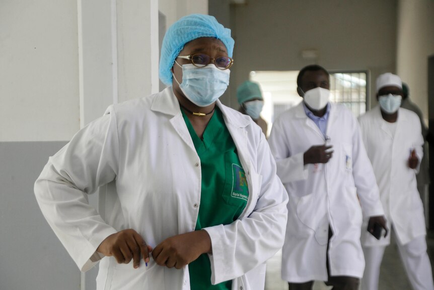 A doctor in PPE looks at the camera.