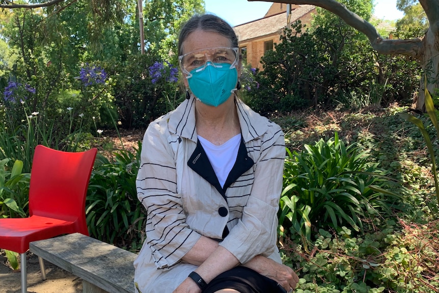 A doctor in goggles and a facemask outside in a garden