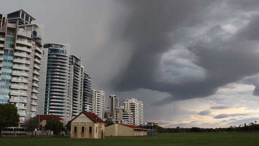 Dark storm clouds over Langley Park with city buildings on the left.