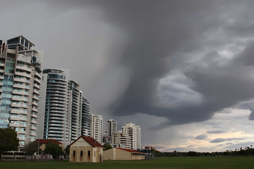 Dark storm clouds over Langley Park with city buildings on the left.