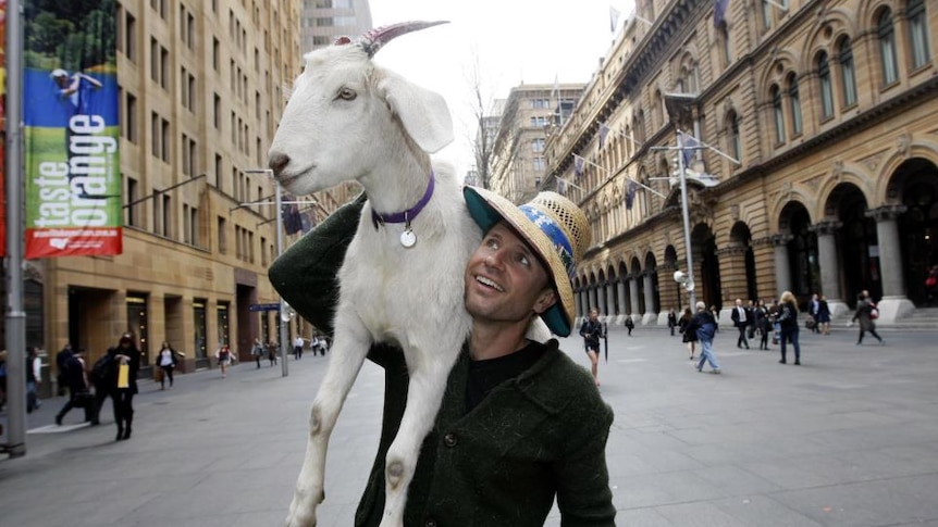 Jimbo Baboozi hold Gary the Goat over his shoulder while walking down the street