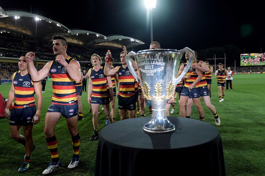 Adelaide players walk past the premiership cup.