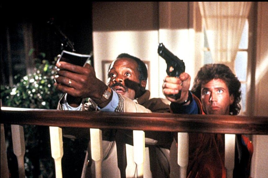 Danny Glover and Mel Gibson hold guns up in a screenshot from Lethal Weapon 