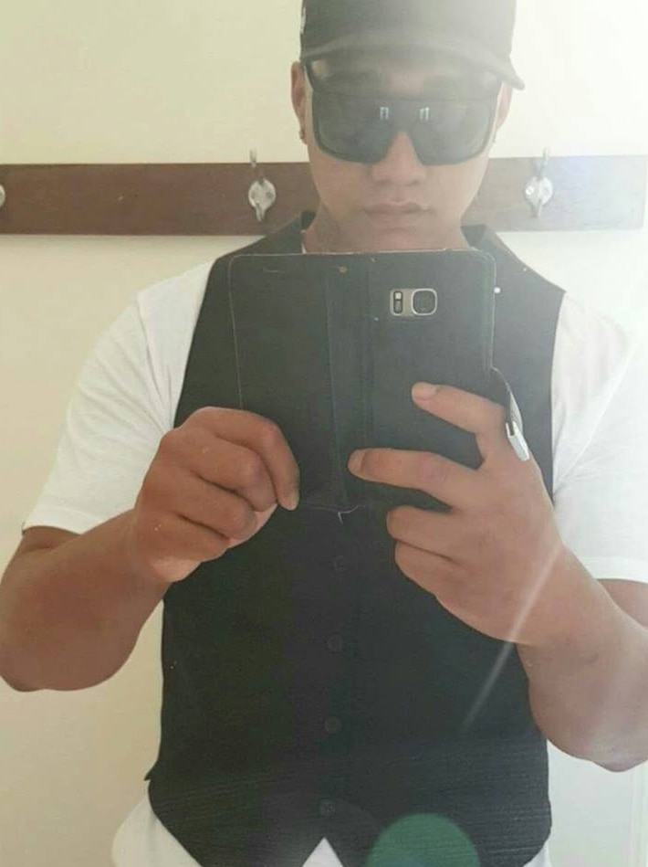 A man in a black baseball cap and sunglasses takes a selfie in a mirror.