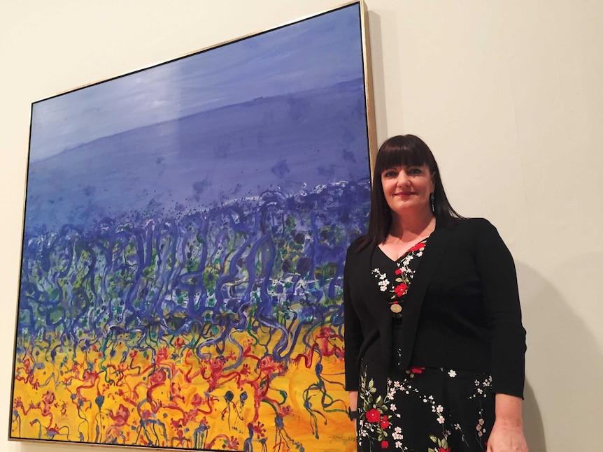 Newcastle Art Gallery manager Lauretta Morton in front of a John Olsen painting.