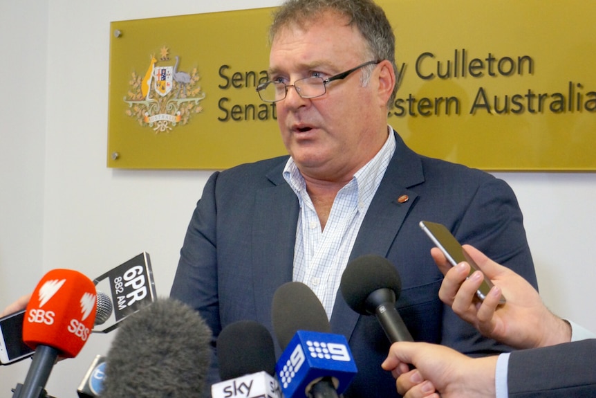 Rod Culleton surrounded by microphones.