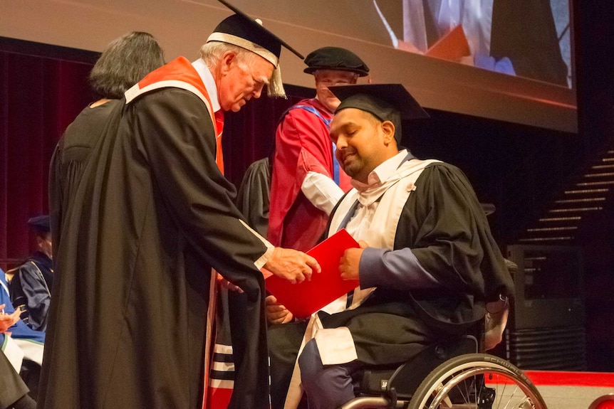 Dinesh Palipana on stage at his graduation being handed his doctorate