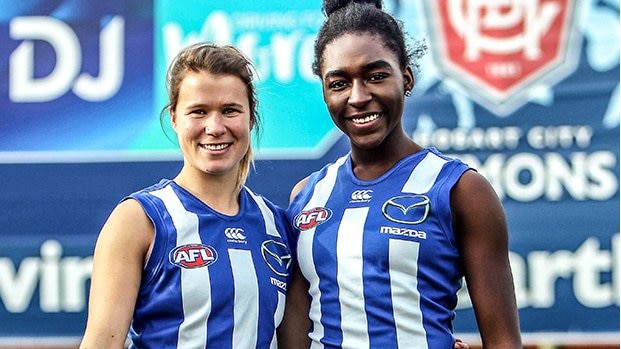 Tasmanians Hannah Squires and Loveth Ochayi in North Melbourne football jumpers.