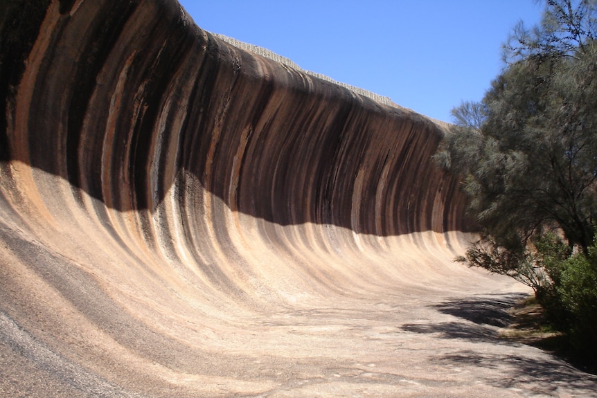 A large reddish rock in the shape of a wave