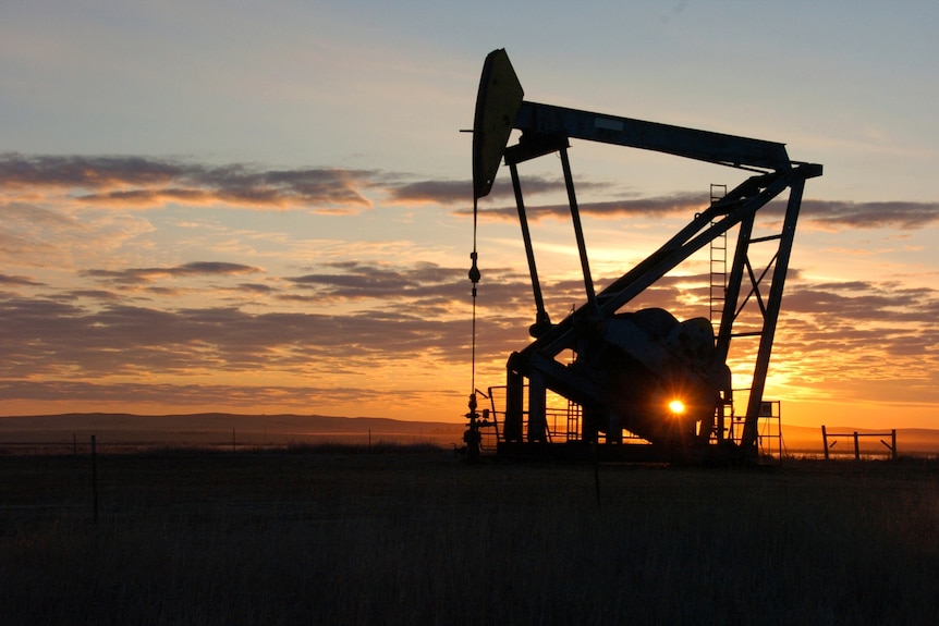 A silhouette of an oil pump in Montana with the sun low in the background