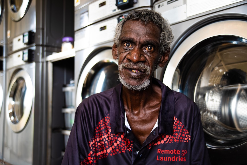 A man sits in front of washing machines in Barunga. 