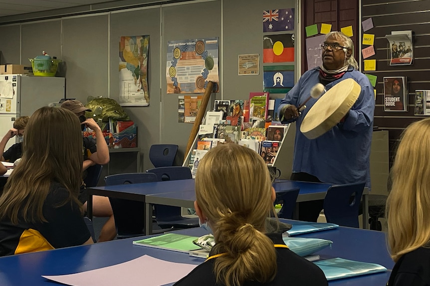 Elder plays drum to attentive students.