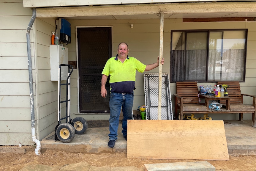 John McCann, wearing a high-vis shirt, stands in front of a house which is being sandbagged.