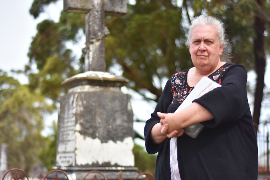 Woman holds ashes at a regional cemetery