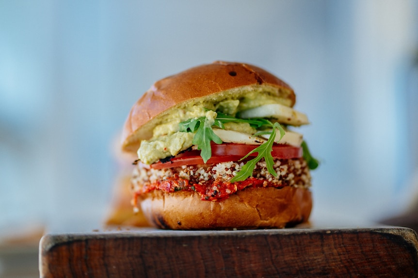 A burger with quinoa, roast capsicum and avocado sandwiched in a bread bun