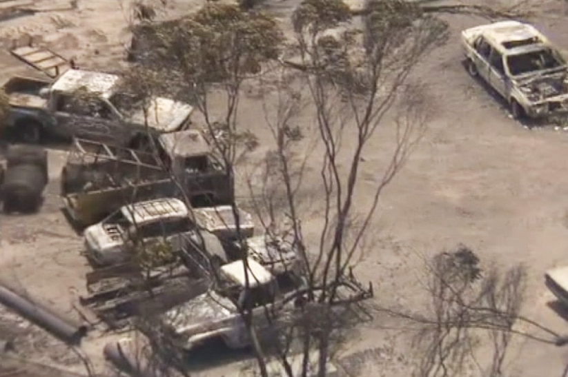 Seven burnt out cars viewed from above on a farm.